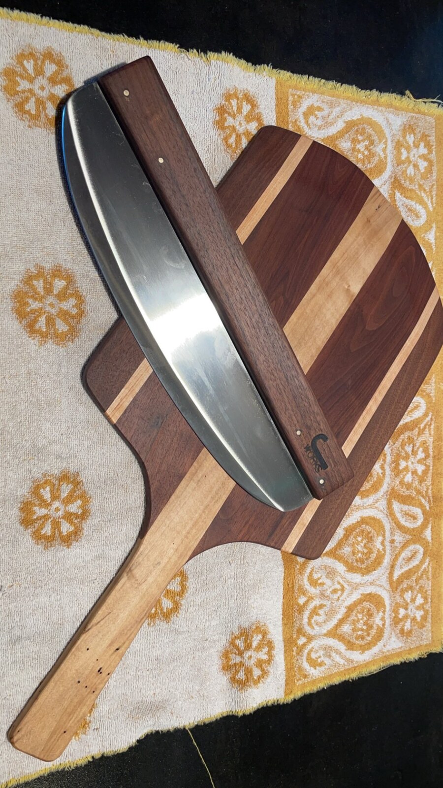 Rocker-style pizza cutter with wood handle on striped board